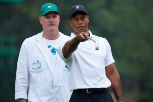 Tiger Woods consulting with caddy to and points putter towards hole to get the right line during the Masters tournament