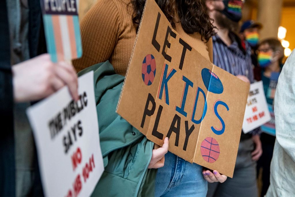 A demonstrator holds a sign in support of inclusion of trans youth athletes in sporting competitions, which House Bill 734 would prohibit.