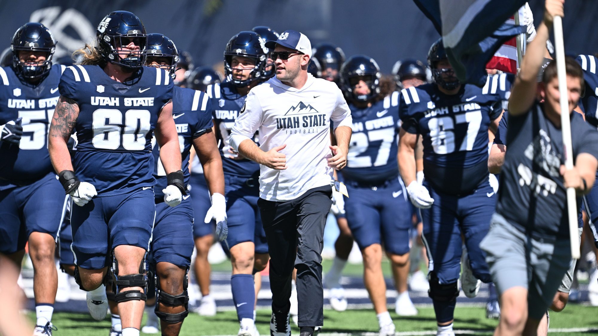 Sep 14, 2024; Logan, Utah, USA; Utah State Aggies interim head coach Nate Dreiling leads his team out onto the field before playing against the Utah Utes at Merlin Olsen Field at Maverik Stadium.