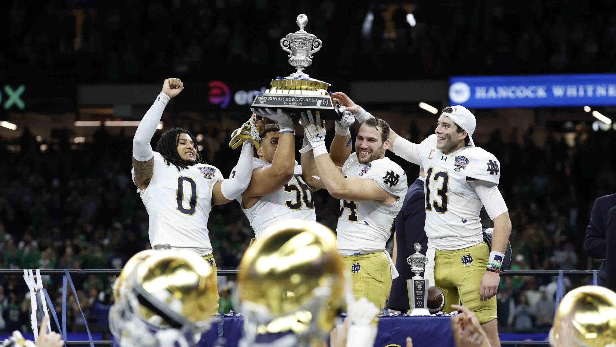 Jan 2, 2025; New Orleans, LA, USA; Notre Dame Fighting Irish safety Xavier Watts (0) Fighting Irish defensive lineman Howard Cross III (56), Fighting Irish linebacker Jack Kiser (24), and Fighting Irish quarterback Riley Leonard (13) celebrate with the Sugar Bowl trophy after their game against the Georgia Bulldogs at Caesars Superdome.