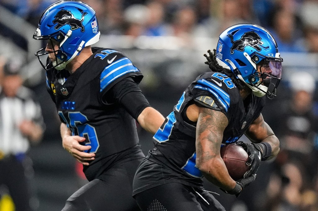 Detroit Lions quarterback Jared Goff (16) hands the ball to running back Jahmyr Gibbs (26).