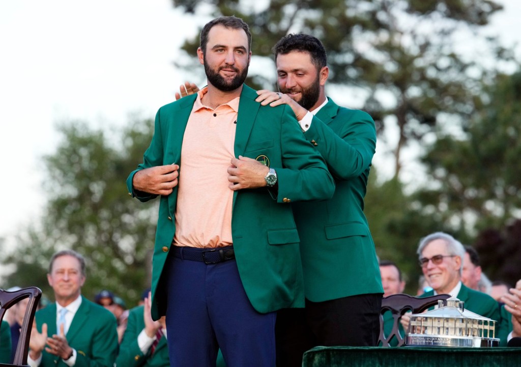 Apr 14, 2024; Augusta, Georgia, USA; 2023 Masters champion Jon Rahm places the green jacket on 2024 Masters champion Scottie Scheffler during the green jacket ceremony following the final round of the Masters Tournament.