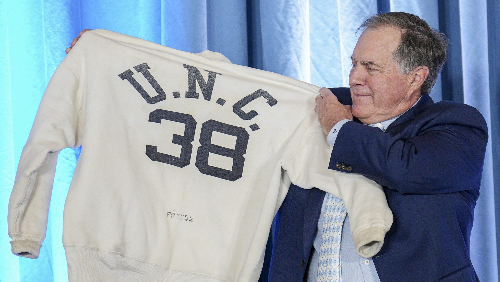Dec 12, 2024; Chapel Hill, NC, USA; North Carolina Tar Heels new head coach Bill Belichick holds up the sweatshirt worn by his father when he was an assistant coach at New North Carolina Tar Heels new at Loudermilk Center for Excellence.