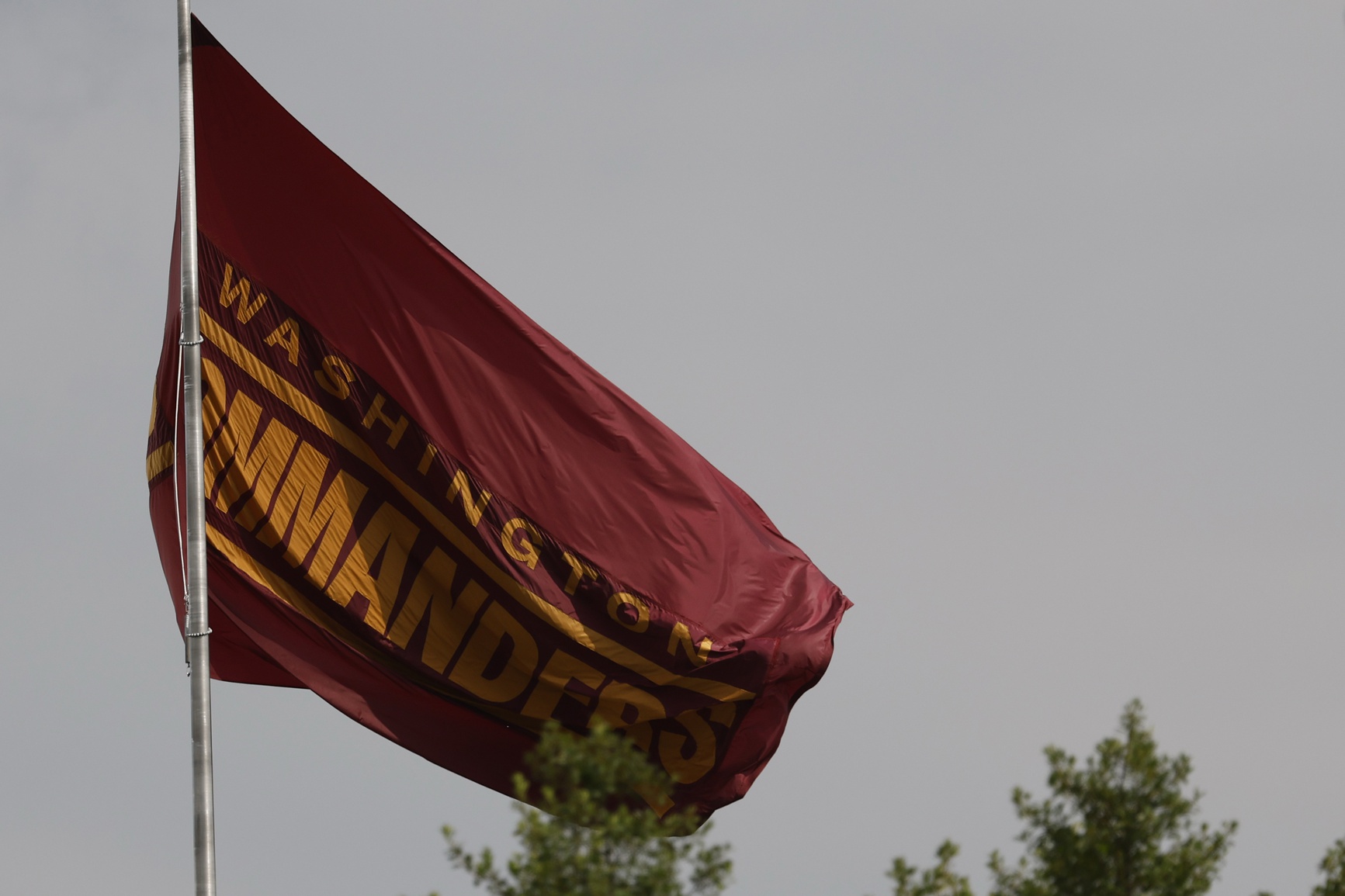 Jul 23, 2025; Ashburn, VA, USA; A view of a Washington Commanders team flag flying in front of team headquarters on day one of training camp at OrthoVirginia Training Center at Commanders Park.