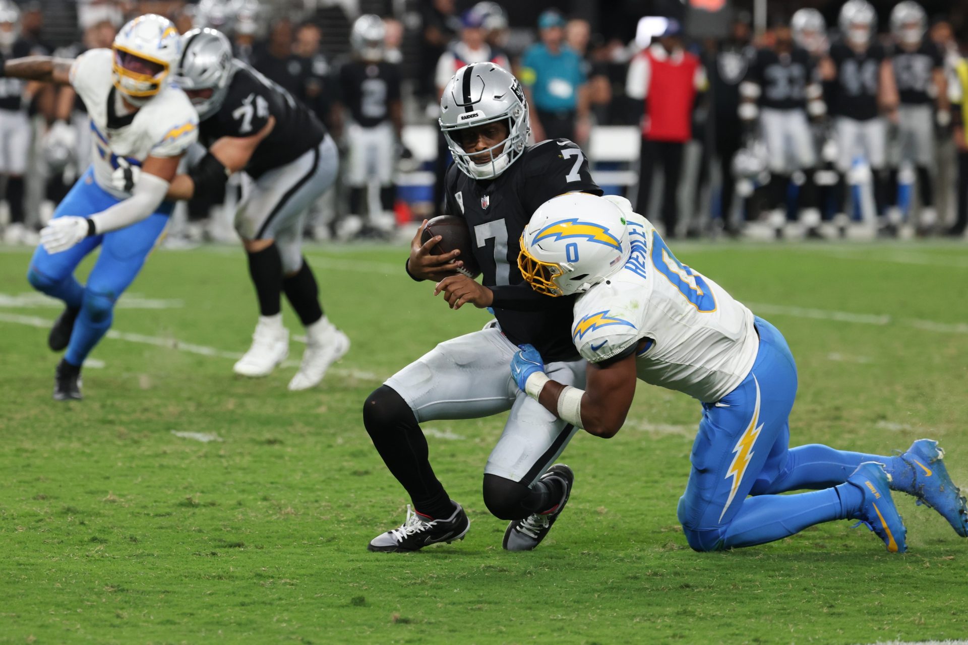 Sep 15, 2025; Paradise, Nevada, USA; Las Vegas Raiders quarterback Geno Smith (7) is tackled by Los Angeles Chargers linebacker Daiyan Henley (0) during the third quarter at Allegiant Stadium.