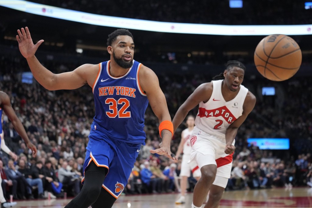 Feb 4, 2025; Toronto, Ontario, CAN; New York Knicks center Karl-Anthony Towns (32) and Toronto Raptors forward Jonathon Mogbo (2) chase after a loose ball during the second half at Scotiabank Arena.