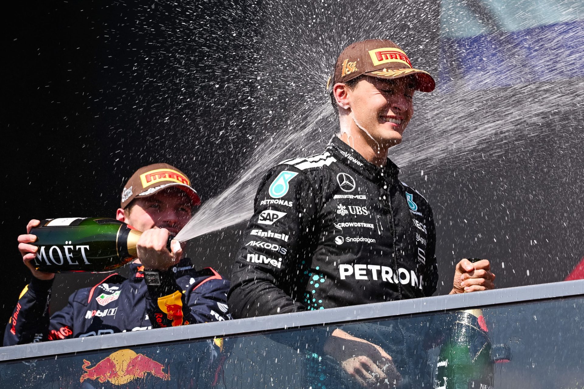 Jun 15, 2025; Montreal, Quebec, Canada; Second place Red Bull Racing driver Max Verstappen (1) sprays champagne on winner Mercedes driver George Russell (63) at Circuit Gilles-Villeneuve.