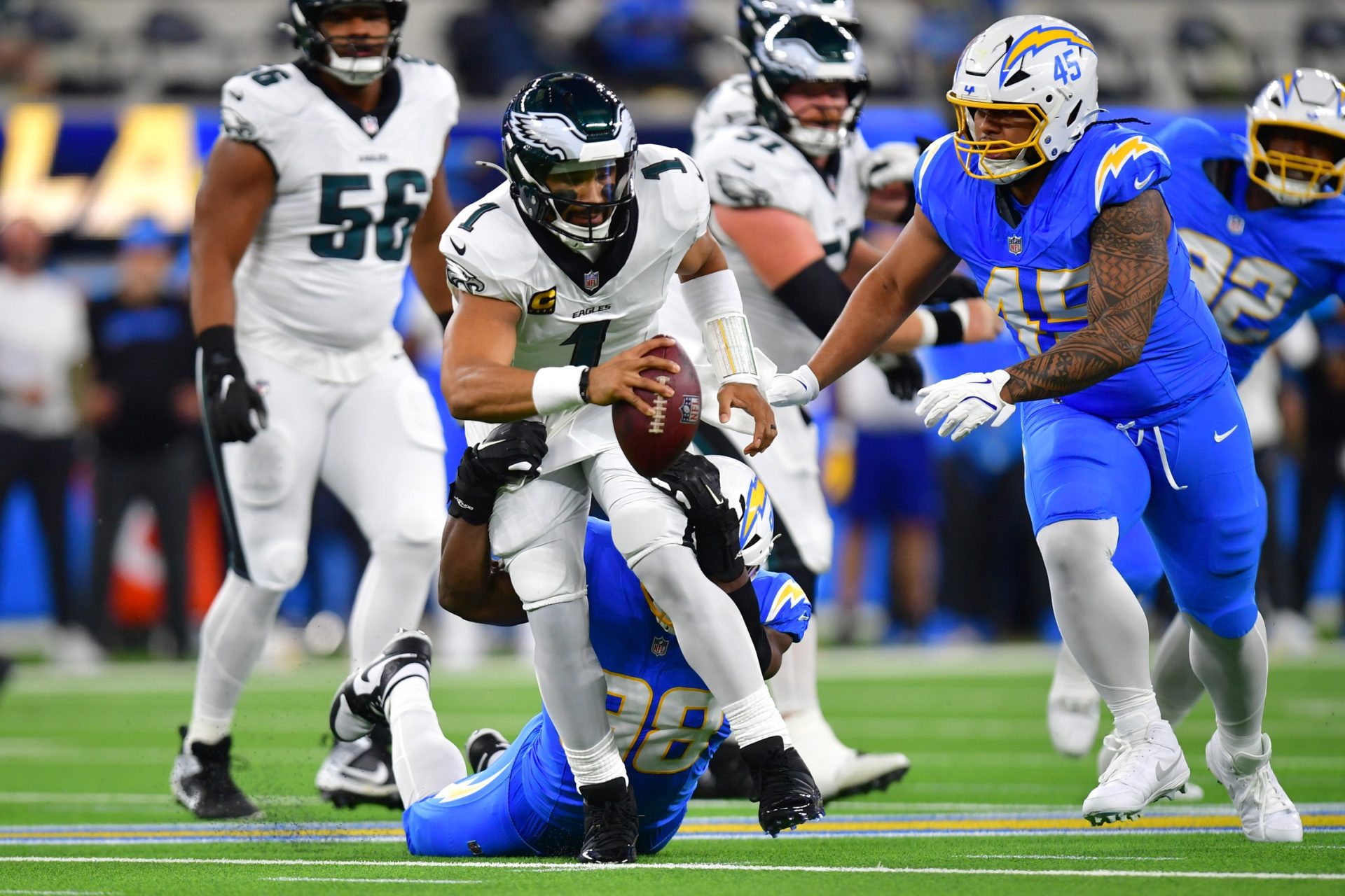 Dec 8, 2025; Inglewood, California, USA; Los Angeles Chargers linebacker Odafe Oweh (98) tackles Philadelphia Eagles quarterback Jalen Hurts (1) in the first half at SoFi Stadium.