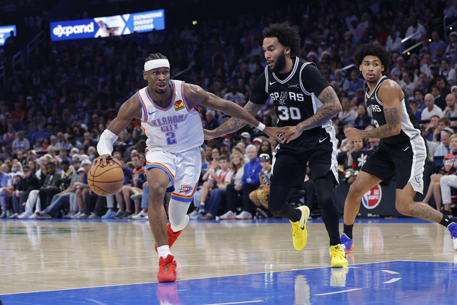 Dec 25, 2025; Oklahoma City, Oklahoma, USA; Oklahoma City Thunder guard Shai Gilgeous-Alexander (2) drives around San Antonio Spurs forward Julian Champagnie (30) during the second half at Paycom Center.