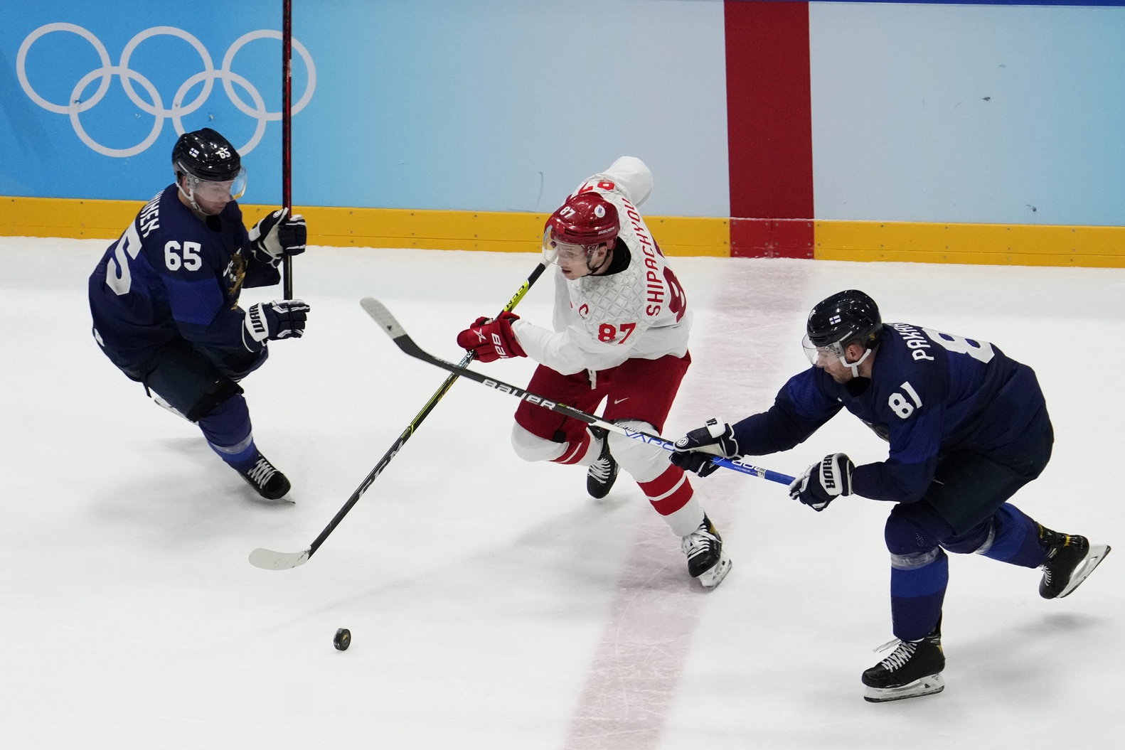 Feb 20, 2022; Beijing, China; Team ROC forward Vadim Shipachyov (87) skates with the puck as Team Finland forward Iiro Pakarinen (81) and Team Finland forward Sakari Manninen (65) defend in the third period during the Beijing 2022 Olympic Winter Games at National Indoor Stadium.
