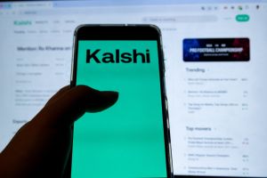In this photo illustration, a mobile device displays the Kalshi logo while a laptop displays the webpage of the prediction market platform in Copenhagen, Denmark, on February 10, 2026. (Photo by Kristian Tuxen Ladegaard Berg/NurPhoto)