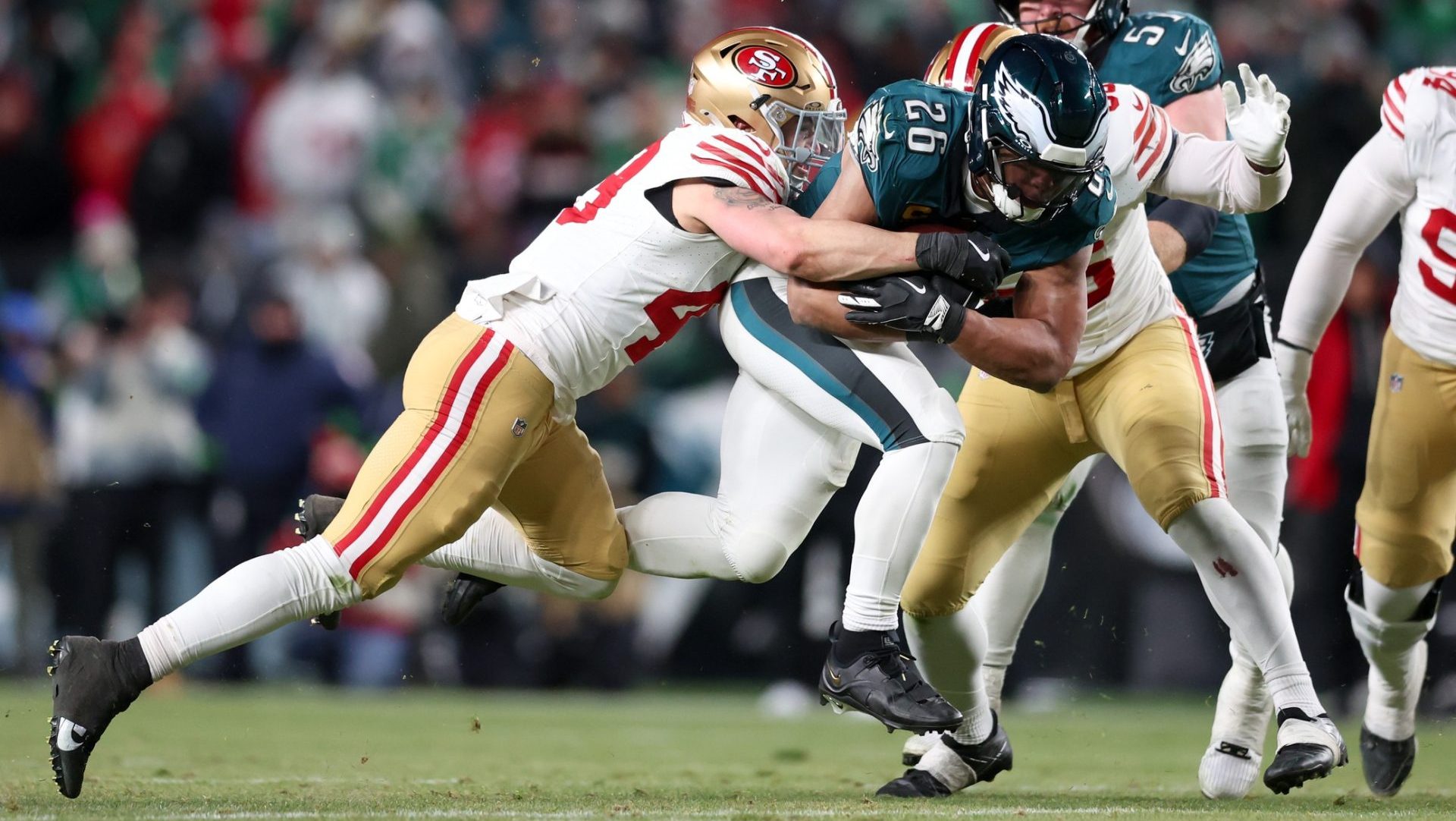 Jan 11, 2026; Philadelphia, PA, USA; Philadelphia Eagles running back Saquon Barkley (26) carries the ball defended by San Francisco 49ers linebacker Garret Wallow (49) and defensive end Keion White (56) during the third quarter in an NFC Wild Card Round game at Lincoln Financial Field.