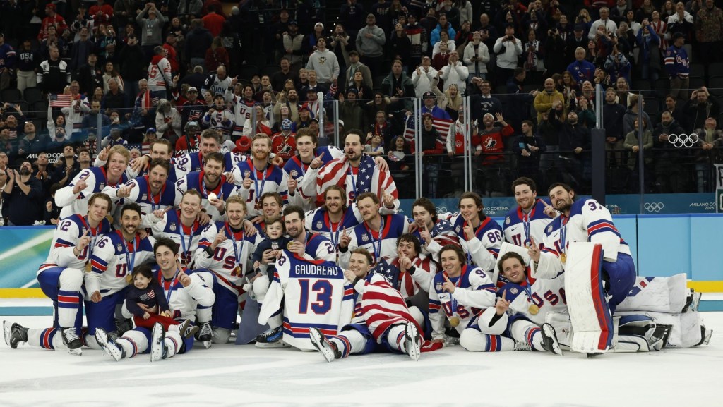 Feb 22, 2026; Milan, Italy; Team United States celebrate on the ice while holding a jersey of their late teammate Johnny Gaudreau after the medal ceremony during the Milano Cortina 2026 Olympic Winter Games at Milano Santagiulia Ice Hockey Arena. Mandatory Credit: Geoff Burke-Imagn Images