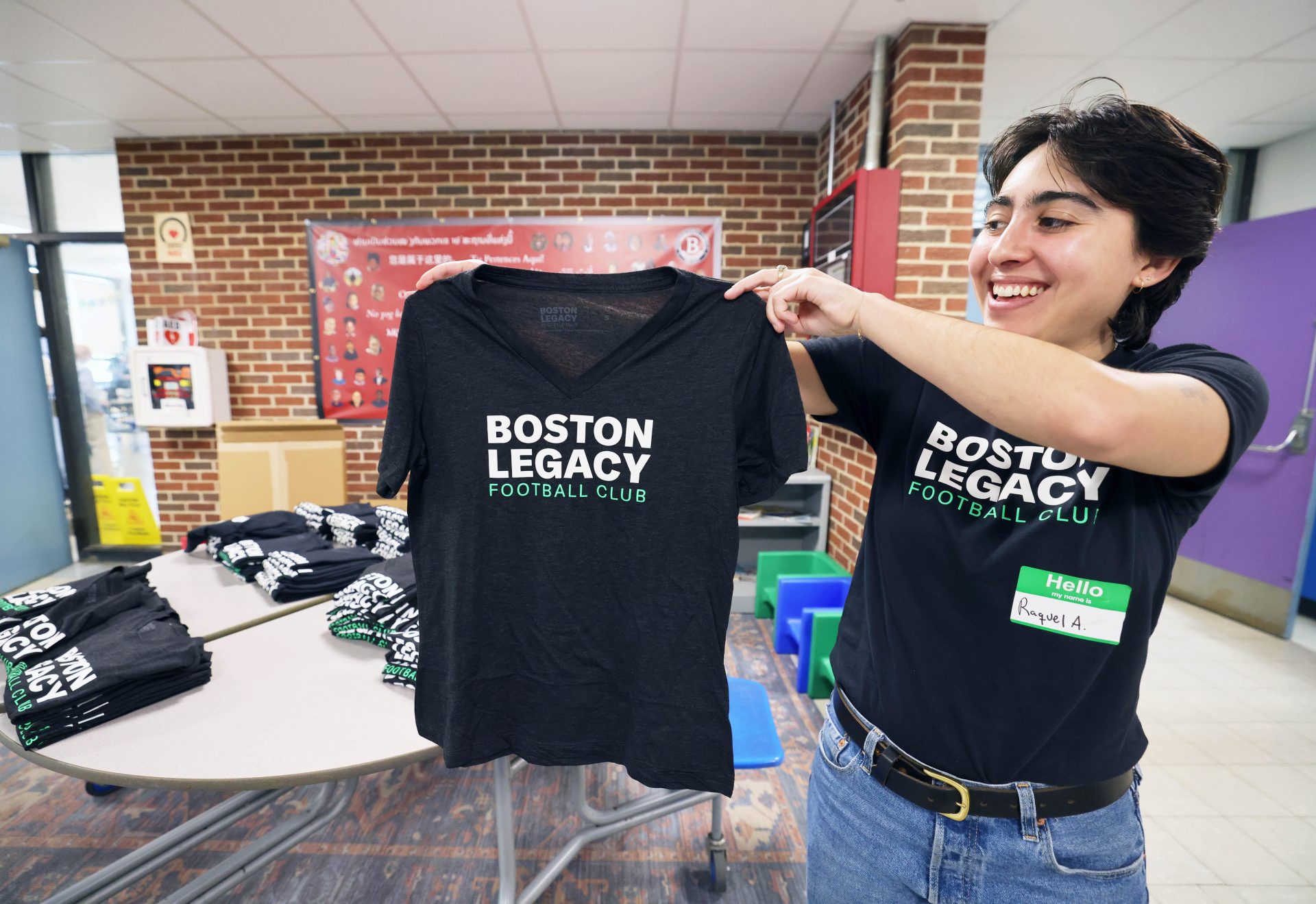 Raquel Aguiree displays a Boston Legacy shirt at a neighborhood meeting on Saturday, May 31, 2025, at Brookfield School to discuss the pro women's soccer team's draft plans for a training facility in Brockton in the old Removal Park area.