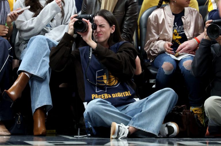 INDIANAPOLIS, INDIANA - MARCH 25: Caitlin Clark of the Indiana Fever sits on the baseline and makes photographs during the Indiana Pacers game against the Los Angeles Lakers at Gainbridge Fieldhouse on March 25, 2026 in Indianapolis, Indiana.