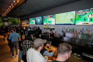 May 9, 2024; Columbus, OH, USA; Sports are shown on TVs behind the bar as guests enjoy the grand opening of DraftKings Sports & Social in the Short North. Though there are no on-site betting windows, eligible customers can place bets through the DraftKings app.