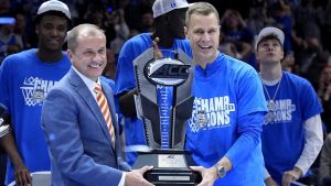 Mar 15, 2025; Charlotte, NC, USA; ACC commissioner Jim Phillips hands the championship trophy to Duke Blue Devils head coach Jon Scheyer after the 2025 ACC Conference Championship game against the Louisville Cardinals at Spectrum Center. Mandatory Credit: Jim Dedmon-Imagn Images