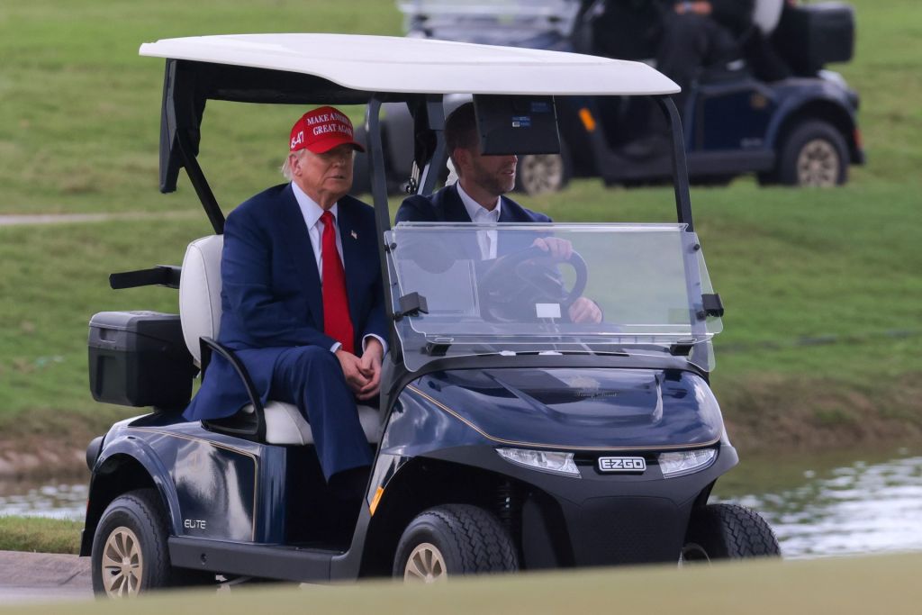Apr 3, 2025; Miami, Florida, USA; President Donald Trump and his son, Eric Trump, drive in a golf cart after he arrived on Marine One at the LIV Golf Miami golf tournament at Trump National Doral.