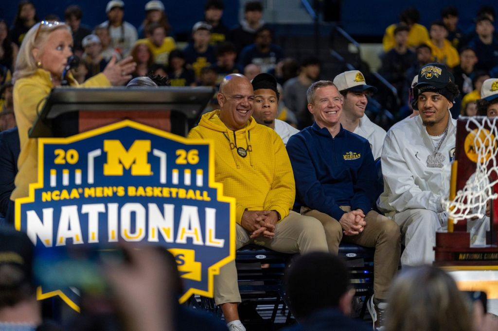 Michigan athletic director Warde Manuel, left, sits and laughs alongside head coach Dusty May and Yaxel Lendeborg during a celebration honoring the team’s NCAA men’s basketball national championship at Crisler Center in Ann Arbor on Saturday, April 11, 2026.